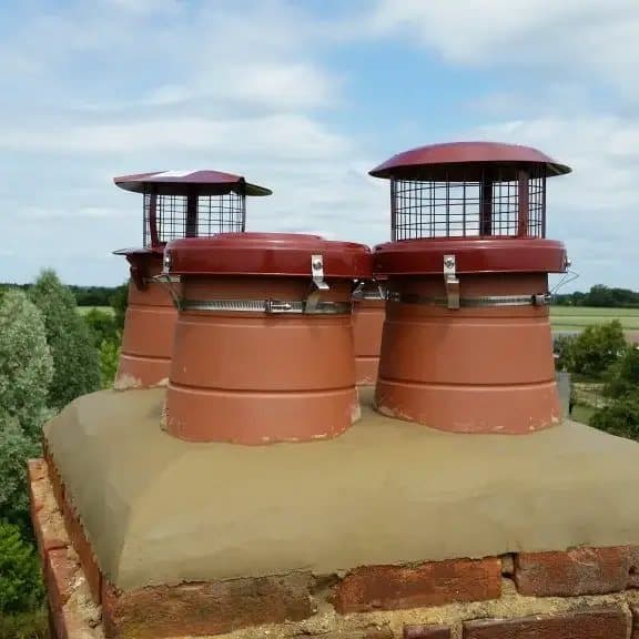 Two terracotta chimney pots fitted with bird guard cowls on a brick stack