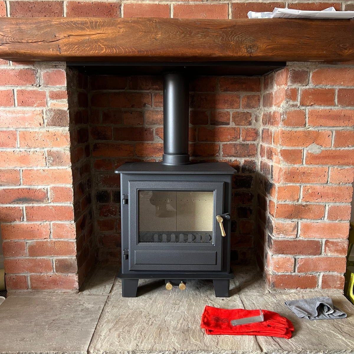 Stove installed in a brick chamber with an oak beam above