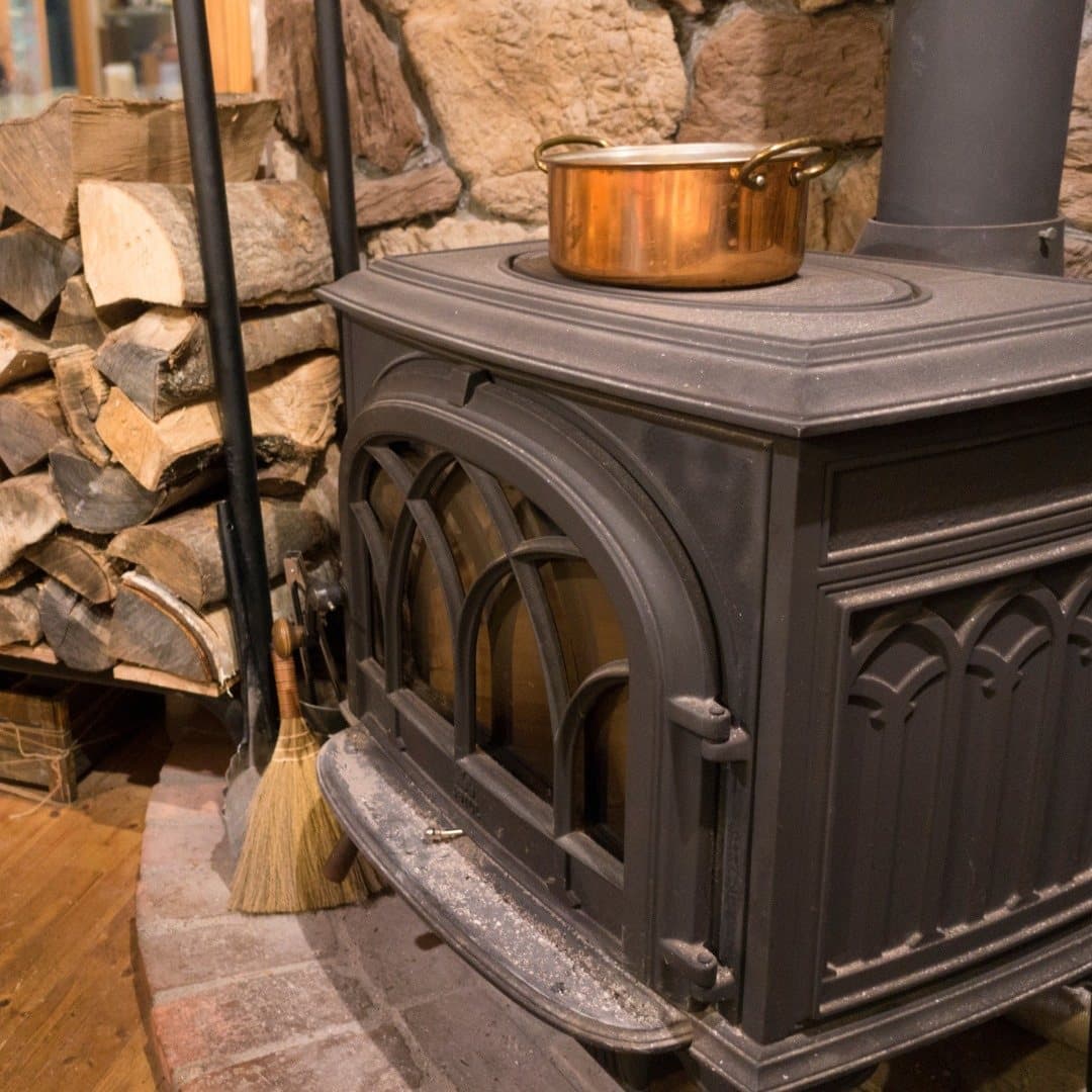 Cast iron stove with a stack of split logs beside it