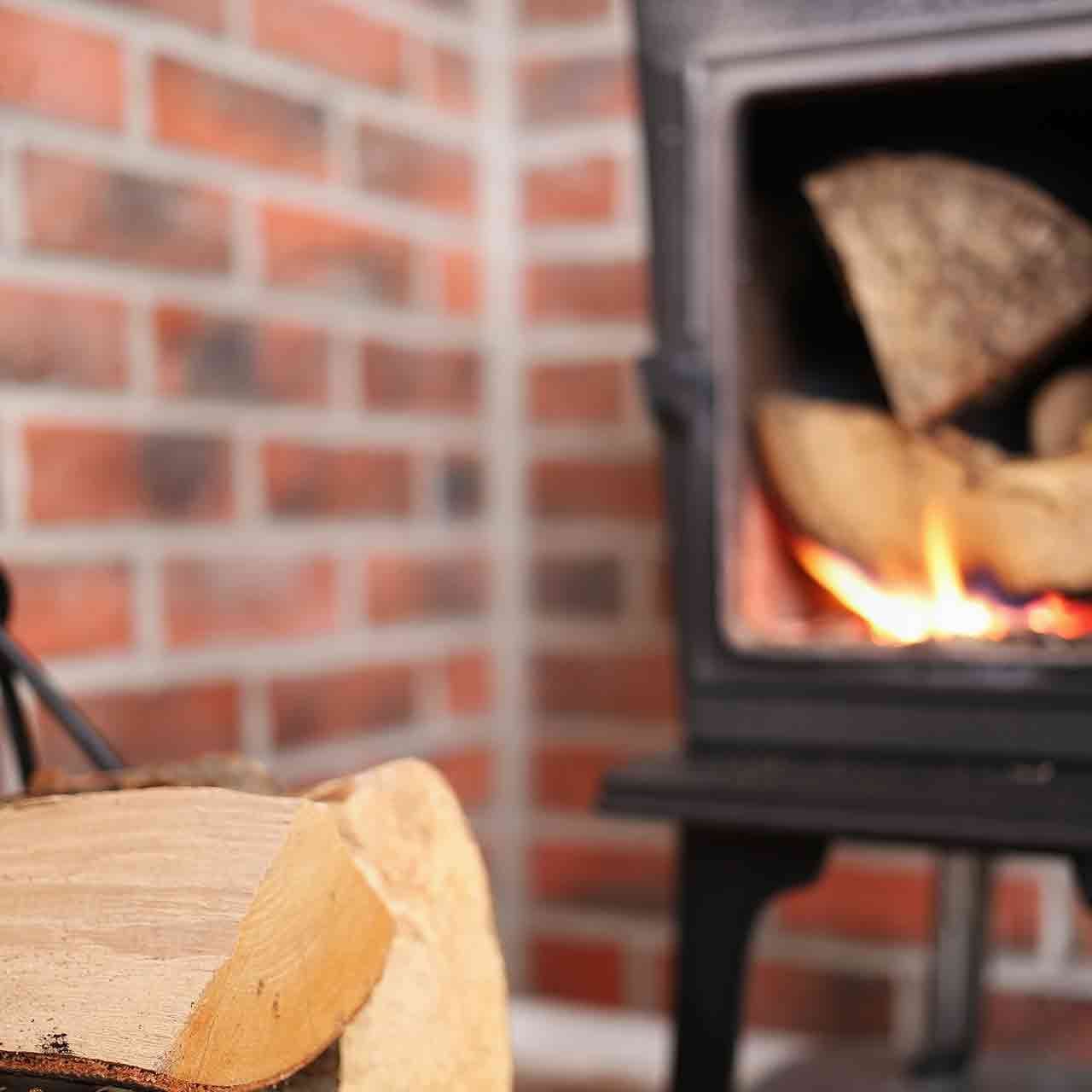 Close up of a stove door rope seal being replaced with firewood stacked beside the stove